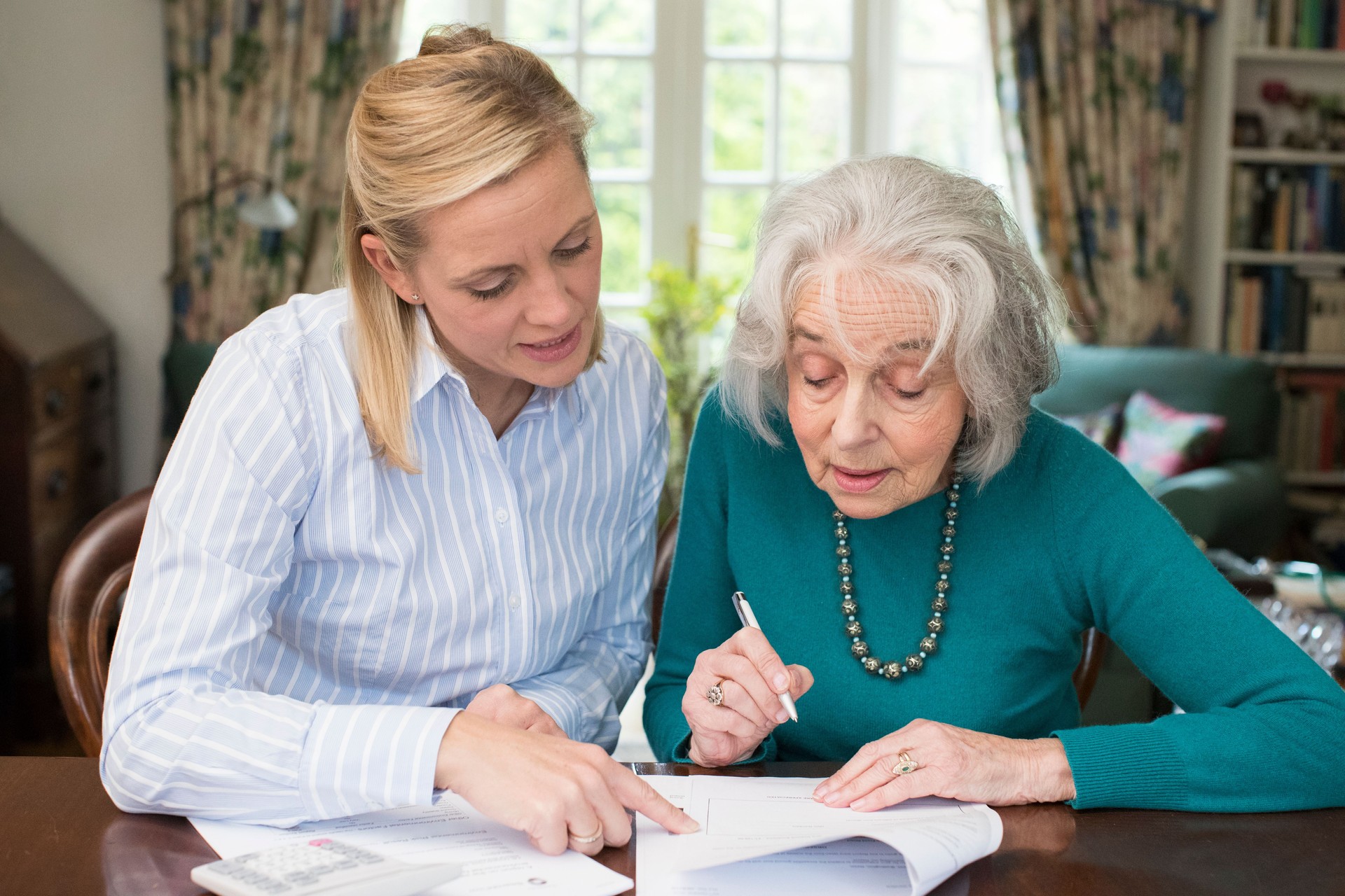 Woman Helping Senior Neighbor With Paperwork